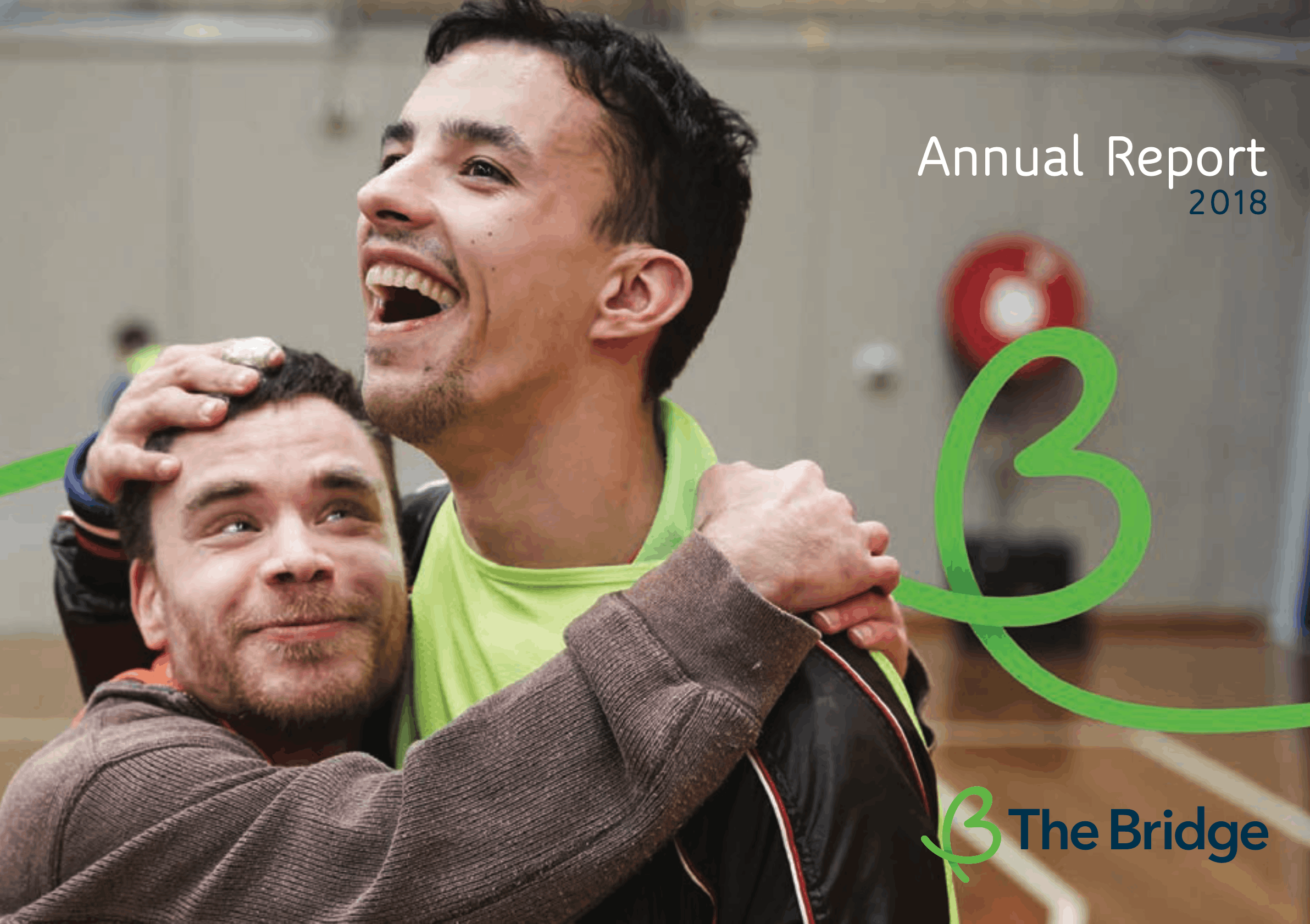 Two men laughing and embracing in a sports hall, cover of The Bridge Annual Report 2018