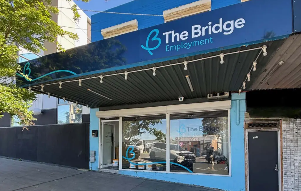 Street view of The Bridge Employment shopfront with blue signage and glass entrance under an awning.