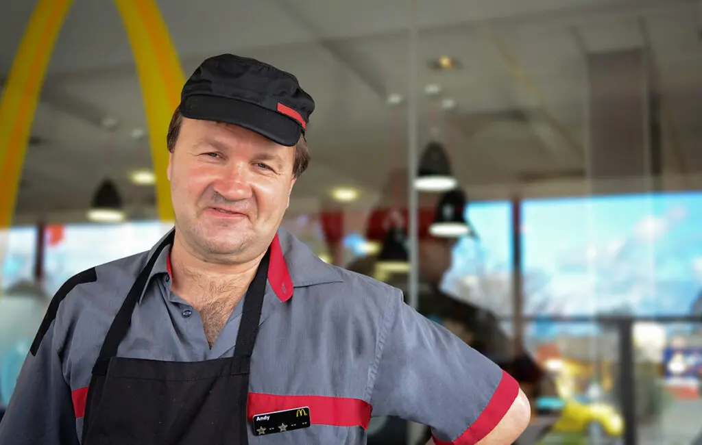 Man in McDonald's uniform and cap smiling, name badge reads Andy, golden arches visible behind
