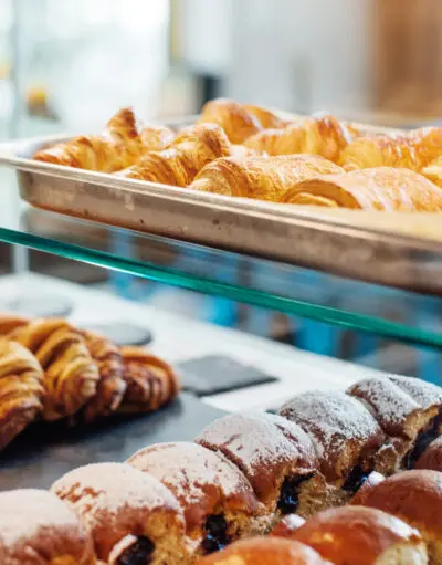 Fresh croissants and sweet pastries displayed in a café cabinet.