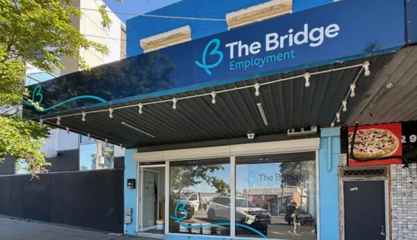 The Bridge Employment shopfront with blue facade, awning and logo, next to a pizza shop sign.