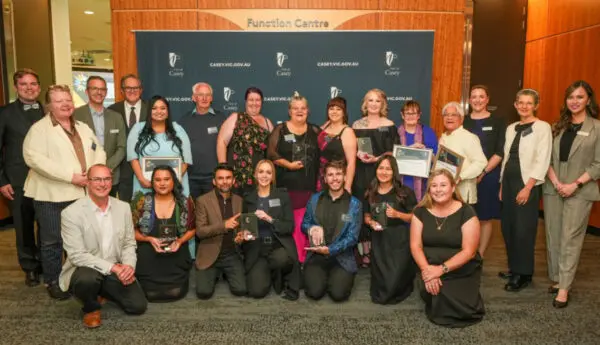 Large group posing with awards and certificates in front of a City of Casey banner at the Function Centre.