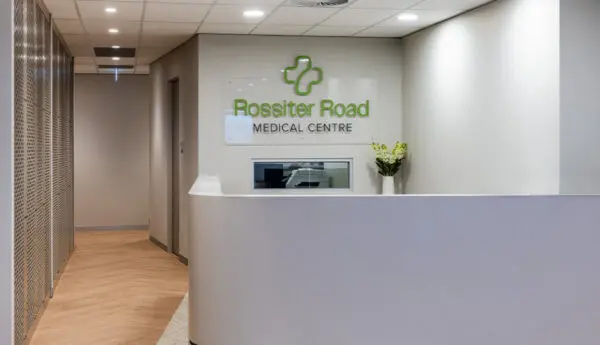 Reception desk with Rossiter Road Medical Centre sign on wall, hallway to the left